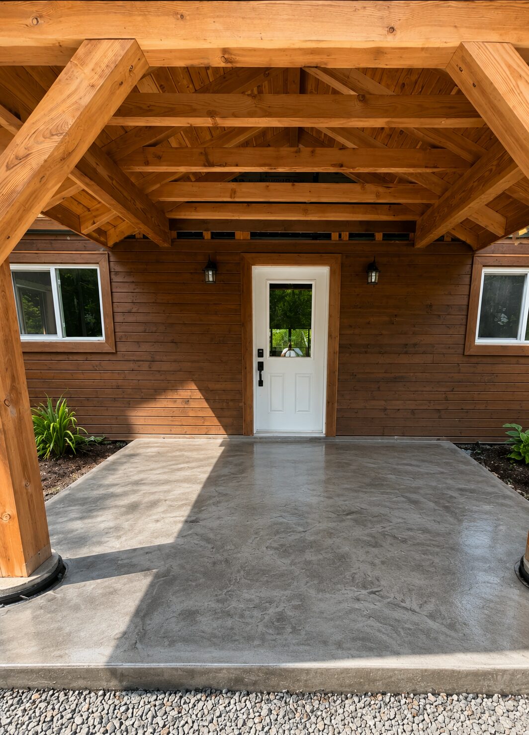 Decorative concrete porch slab in front of a wood-clad home
